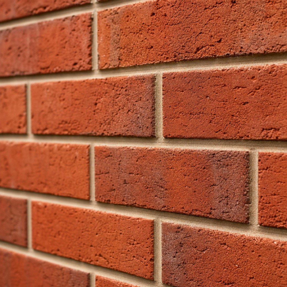 Close-up of a freshly laid red brick wall with crisp tooled mortar joints